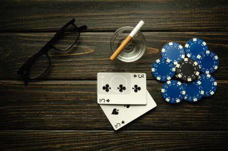 Foto de Jugar al póquer con una combinación ganadora de un par. Tarjetas con papas fritas y vasos con un cigarrillo en una mesa vintage negra en un club de poker. - Imagen libre de derechos