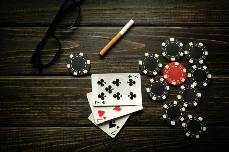 Photo for Playing cards with a winning combination of three of a kind or set with chips on a black vintage table. Winning in sports or poker depends on luck - Royalty Free Image