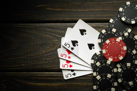 Photo for Playing cards with a winning combination of four of a kind or quads on a dark vintage table in a poker club. Winning in sports depends on luck. - Royalty Free Image