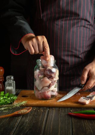 Photo for Filling the jar with chopped fish steaks. The process of salting or canning fish at home with spices and coriander. - Royalty Free Image