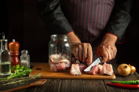 Photo for The cook cuts raw fish into steaks for canning in a jar. Delicious salted fish dinner for a restaurant. - Royalty Free Image