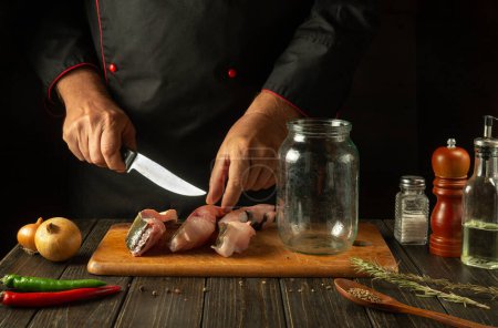 Photo for Cutting fish into steaks before salting in a jar. The concept of preparing a fish dish or herring with the hands of a chef in the kitchen. - Royalty Free Image