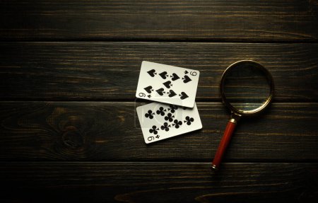 Foto de Juego de juego de póquer con una combinación de pares. Lupa y tarjetas en una mesa vintage negra en un club de poker. - Imagen libre de derechos