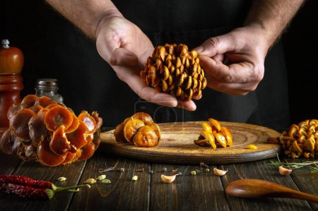 Ein Koch sortiert Pilze mit seinen Händen in der Küche, bevor er sie mit Gewürzen kocht. Ernährungskonzept für Pilze.