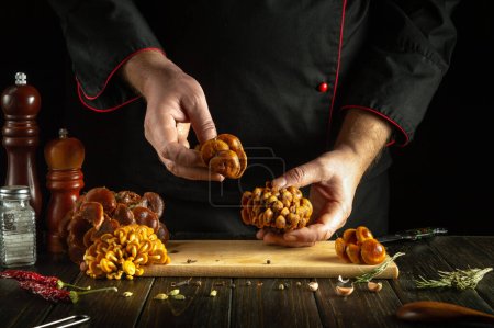 Frische rohe Pilze in den Händen eines Küchenchefs. Pilze sortieren und reinigen vor dem Kochen in der Hausküche.