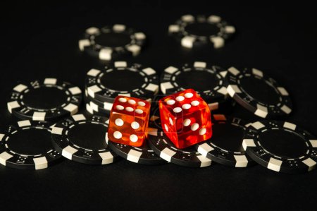 Dice and chips from winnings on the craps black table in the club. Fortune in the game depends on a successful combination in the game of dice.