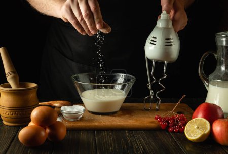 Der Koch salzt ein Milchgericht in einer Schüssel auf dem Küchentisch. Das Konzept der Zubereitung eines leckeren Omeletts mit Eiern und Milch in einer Restaurantküche.