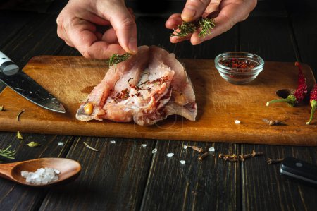 Cocinar filete de pescado por las manos de un chef en la mesa de la cocina. Añadir romero para el sabor y el aroma al pescado de merluza.