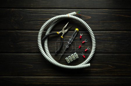 Photo for White corrugated cable and a set of tools on a vintage table for electrical repair. Concept of replacing or connecting electrical equipment. - Royalty Free Image