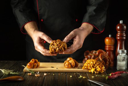Samthandschuh in den Händen eines Kochs, bevor er sortiert und in einer Restaurantküche zubereitet wird. Leckeres Mittagessen mit frischen rohen flammulina velutipes.