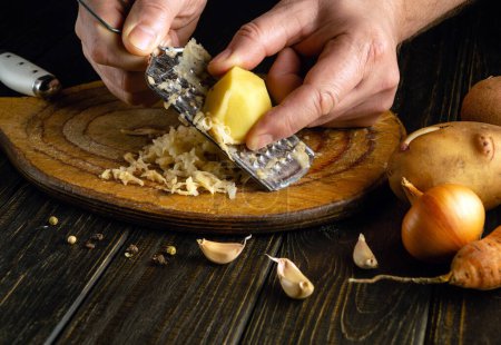 Koch reicht geriebene Kartoffeln aus nächster Nähe. Low-Key-Konzept von gesunder pflanzlicher Ernährung und biologischer Ernährung.