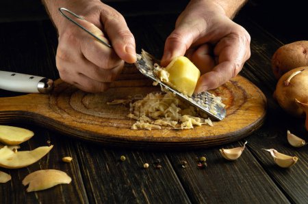 Die Hände der Köchin reiben die Kartoffeln zu Kartoffelkuchen. Konzept der Zubereitung von Gemüsemenüs zum Frühstück.