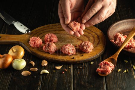 Close-up of a chef hands forming meatballs from minced meat. Low key concept of cooking a meat dish for lunch.