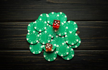 Green chips on a vintage dark table from a successful combination in a game of dice or craps. Low key concept of a gambling and popular game.