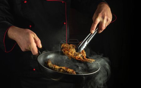 Concept clé bas de la préparation d'un plat de poisson dans une cuisine de pub. La cuisson des frites de poisson dans une poêle chaude. Espace sombre pour la publicité.