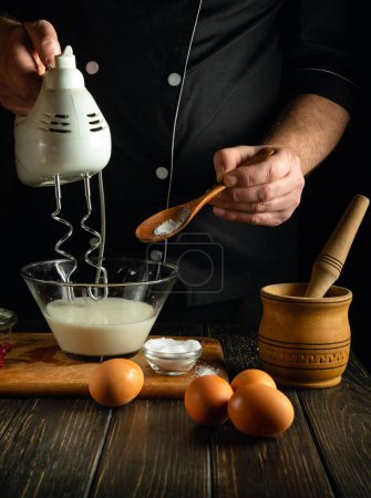 El chef saltea un plato de leche en un tazón en la mesa de la cocina. Concepto bajo en clave de preparar deliciosa tortilla con huevos y leche en la cocina de taberna.