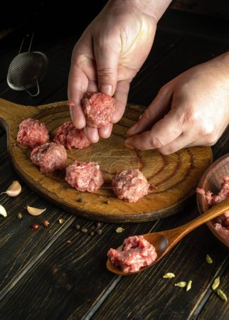 Le cuisinier fait des boulettes de viande à partir de viande hachée sur la table de cuisine. Concept clé bas de préparer un délicieux déjeuner.