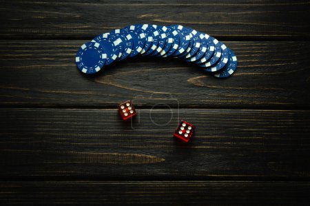 Blue chips on a vintage dark table from a successful combination in a game of dice or craps with two sixes. Low key concept of a gambling and popular game.