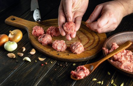 Cooking meatballs with minced meat by the hands of a chef on the kitchen table for lunch.
