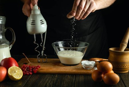 El cocinero agrega sal a la leche para preparar una tortilla de huevo en la mesa de la cocina. Concepto bajo de cocina deliciosa comida con leche y huevos.