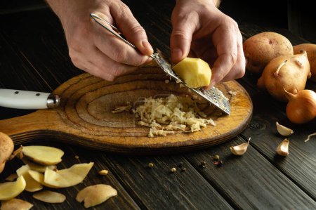 Ein Gericht mit geriebenen Kartoffeln mit den Händen eines Küchenchefs auf dem Küchentisch zubereiten. Kleines Konzept zum Kochen von Gemüsemenüs.