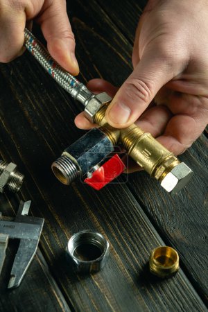 Bajo concepto clave de reparación de equipos de gas por las manos de un artesano en un taller sobre la mesa. Conexión de accesorios a la manguera.