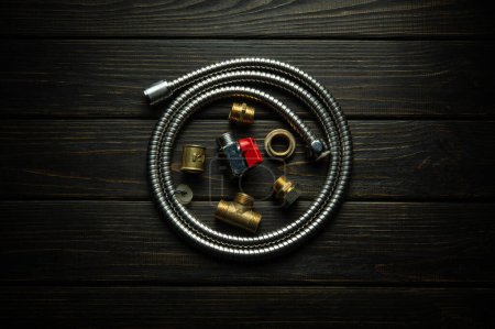 Flexible hose and brass fittings on antique dark boards. Low key concept for construction and repair of gas equipment.