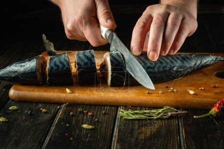 Chef preparando caballa fresca en la mesa de la cocina. Concepto bajo en clave para preparar un plato de pescado. Rebanando pescado Scomber con un cuchillo.