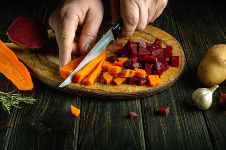 Foto de Cortar verduras hervidas con un cuchillo en las manos de un chef para preparar una ensalada. Concepto de baja tecla para cocinar menú vegetal. - Imagen libre de derechos