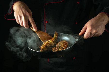 In der Küche gebratenen Kakerlakenfisch zubereiten. Fisch in der Pfanne in den Händen eines Küchenchefs kochen oder braten. Leckere Fischgericht-Idee.