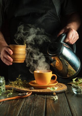 Ein Mann bereitet aromatisch gesunden Tee aus Heilkräutern auf dem Küchentisch zu. Werbefläche.