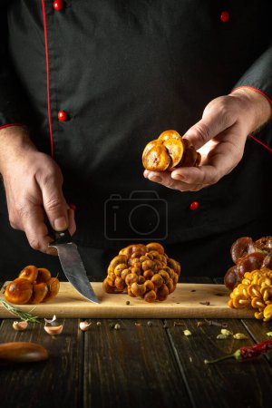 El cocinero prepara setas frescas de terciopelo en la cocina del restaurante. El concepto de preparar hongos silvestres dietéticos Flammulina velutipes para el desayuno.