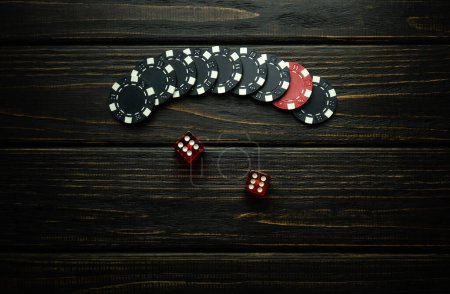 Rote Würfel und Gewinnchips auf einem dunklen Vintage-Tisch in einem Pokerclub. Erfolgreiche Kombination zweier Sechsen im Würfel.