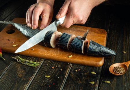 Der Koch bereitet in der Küche frische Makrelen zu. Vor dem Backen muss der Fisch in kleine Stücke geschnitten werden. Idee der Fischernährung.