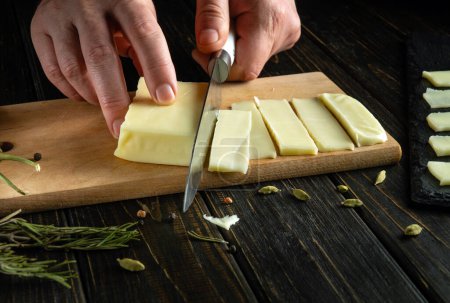 Table setting for breakfast. Chef hands use a knife to cut cheese on a kitchen board. Advertising space. 