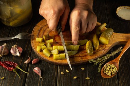 The process of preparing a delicious national Ukrainian dish with pickles. Knife in the hand of a cook for cutting salted cucumber.
