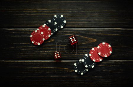 Würfel und Gewinnchips auf einem schwarzen Vintage-Tisch in einem Pokerclub. Erfolgreiche Kombination zweier Sechsen in Würfeln. Erfolgreiches Konzept des Clubs.
