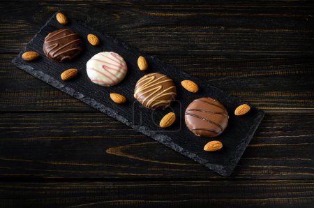 Schokokekse oder Schokoladenbrownie auf einem schwarzen Servierbrett mit Nüssen. Leckeres Dessert-Konzept für ein Restaurant oder Shortbread-Plätzchen-Idee für Millionäre.
