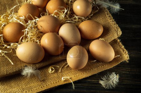 A large pile of eggs with straw and feathers. Chicken eggs are collected to make a healthy breakfast. Harvest concept.