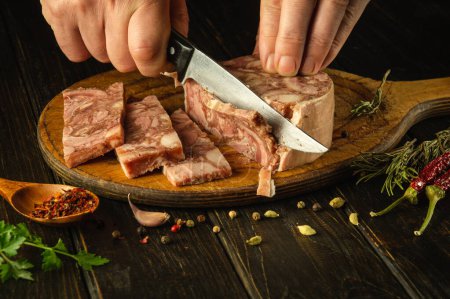 Slicing headcheese on a kitchen board before setting the table in a restaurant for dinner. Knife in the hand of a chef while cutting brawn