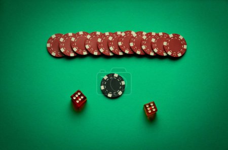 Dice and winning chips on a green table in a poker club. A successful combination of two sixes in a dice. Concept of winning in a casino.