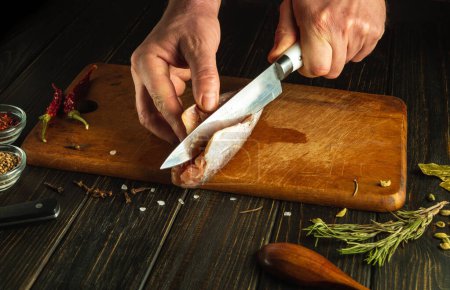 Der Koch putzt frischen Fisch mit einem Messer, bevor er auf dem Küchentisch kocht.
