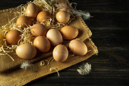 A pile of chicken eggs with straw and feathers. Eggs are collected to make a healthy breakfast or dinner. Advertising space.