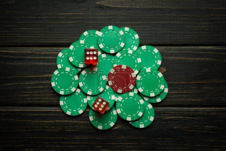 Chips auf einem dunklen Tisch aus einer erfolgreichen Kombination in einem Würfelspiel mit zwei Sechsen. Low-Key-Konzept des Glücksspiels und beliebtes Spiel Craps.