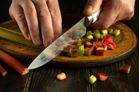 The cook cuts up some rhubarb stalks to add to the food at dinner for flavor and extra taste.