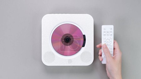 Elegante reproductor de CD compacto portátil blanco con disco de CD rosa que reproduce música y controlador de mano sobre fondo gris. Retro vintage de tendencia reproductor de discos. Hobby entretenimiento ocio