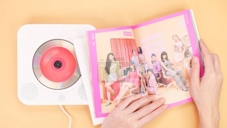 Photo for Hands holding Twice Between 1 and 2 mini Album photobook on yellow. Music CD player. South Korean girl group Twice. Space for text. Gatineau, QC Canada - December 27 2022 - Royalty Free Image