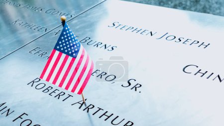 Photo for Memorial at Ground Zero Manhattan for September 11 Terrorist Attack with an American Flag Standing near the Names of Victims Engraved. Patriot Day - New York NY USA 2023-07-30. - Royalty Free Image