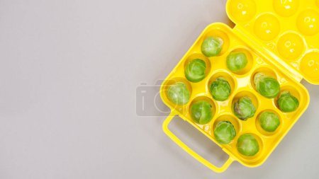 Photo for Raw organic Brussel sprouts in yellow container on grey background, top view. Flat lay, overhead, from above. Copy space - Royalty Free Image
