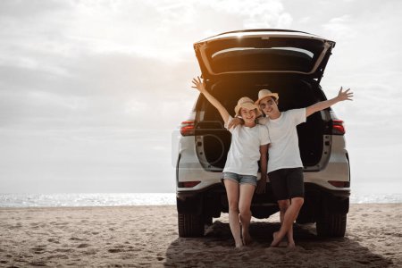 Photo for Car road trip travel of couple enjoying beach relaxing on hood of sports utility car. Happy Asian woman, man friends smiling together on vacation weekend holidays on the beach. - Royalty Free Image
